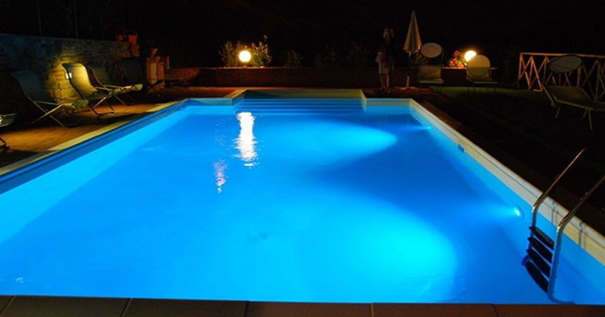 A pool at nighttime with lights on
