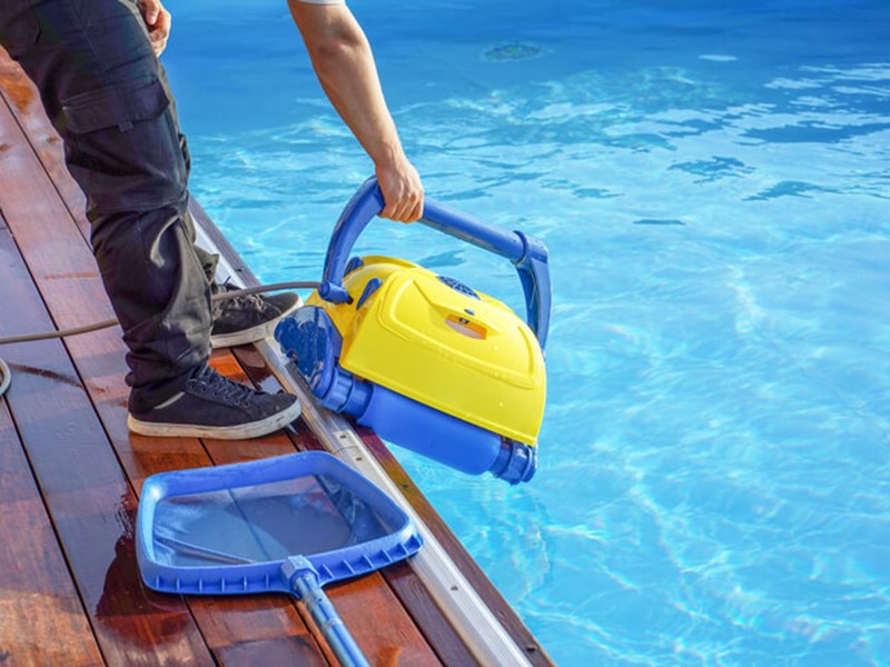 Man putting cleaning machine into pool